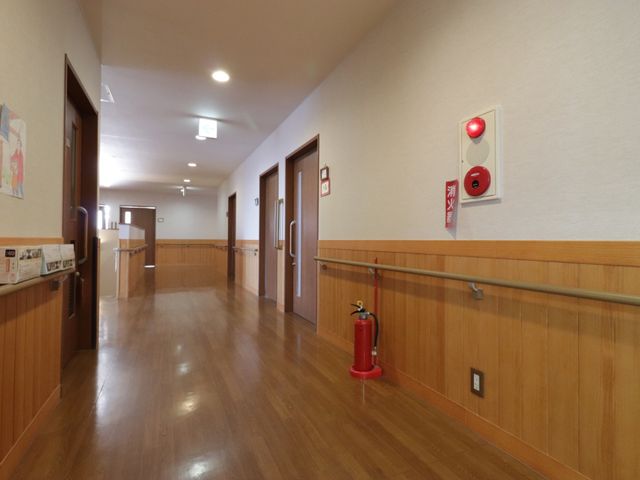 清潔感のある明るい廊下 廊下 手すりが設けられた安全な通路です。壁には心温まるイラストも飾られ、明るく家庭的な雰囲気が感じられます。