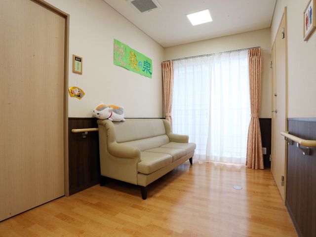 快適な居室空間 ソファー1 明るくゆったりした居室で、窓からの自然光が心地よい空間を演出します。手すりも設置されており、安心して過ごせる環境が整っています。