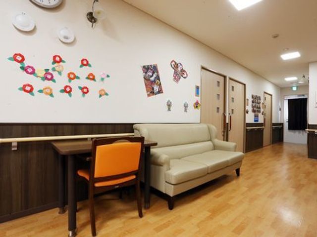 ソファが設置された廊下 談話コーナー 広々とした廊下には、柔らかなソファがあり、壁には色とりどりの飾りがあしらわれています。休憩時にくつろぐことができる心地よい空間です。