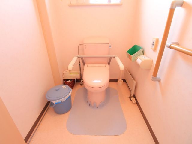 バリアフリー設計のトイレ トイレ 手すり付きで安全性を考慮した快適なトイレです。利用者の日常生活をサポートするための配慮が感じられます。