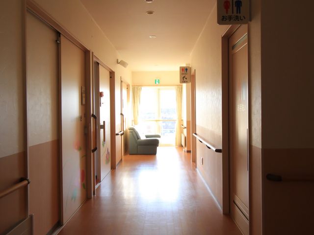 明るい廊下とリビング 通路 陽光が差し込む廊下の先には、ゆったりとくつろげるリビングスペースがあります。訪れる方々の心地よいひと時を提供します。