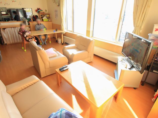 リラックスできる共有スペース 談話室 陽光が差し込む心地よいラウンジで、利用者様同士が椅子に座ってくつろぎや会話を楽しんでいます。