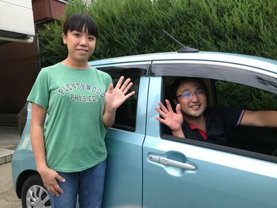 笑顔で手を振るスタッフと車