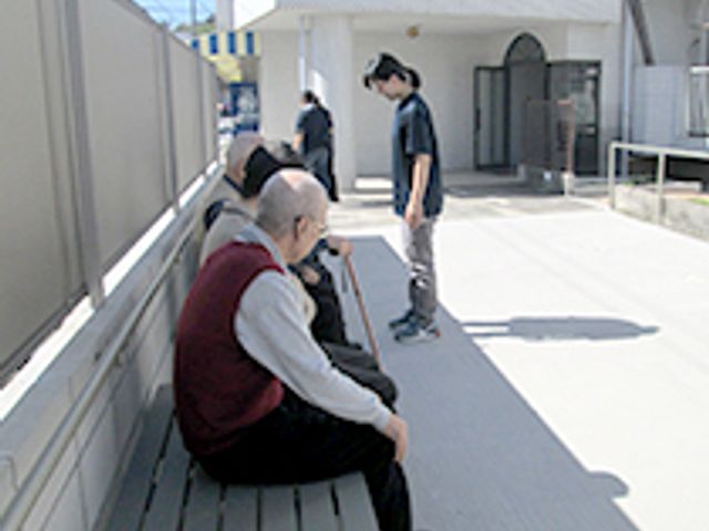 談笑する人々の庭 庭 青空の下で、ベンチに座りリラックスできる外のスペースが設けられています。交流の場として人気です。
