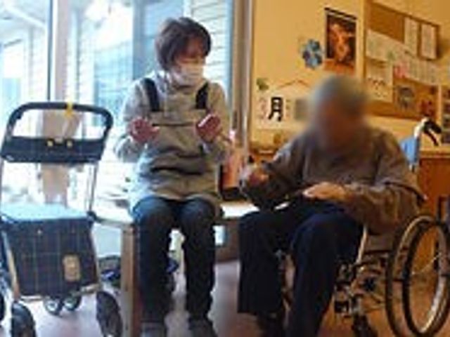 談笑する二人の様子 内観 自然光が差し込み、日中の活動が快適に行われている様子です。スタッフと利用者が親しげに談笑しています。