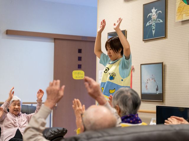 スタッフと利用者の笑顔あふれる場面 機能訓練室 明るい表情で利用者と積極的に関わり、楽しい時間を提供するスタッフの姿から、職場の温かな雰囲気が伝わります。