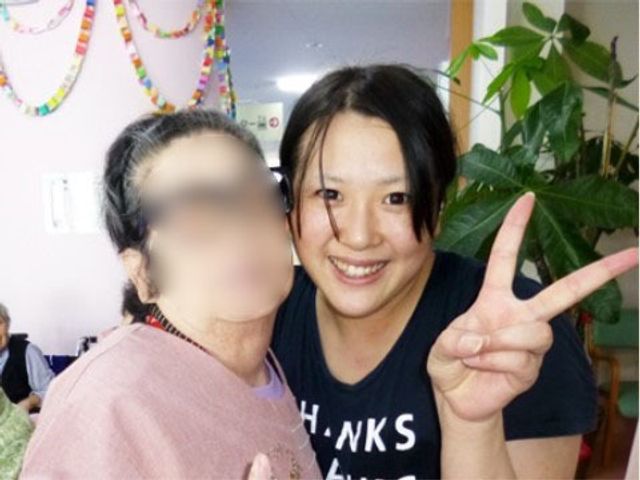 笑顔あふれる居室の様子 入居者様 スタッフと利用者の温かな交流が感じられる明るい居室。手を挙げているスタッフの元気な表情からは、やりがいのある職場環境が伝わります。