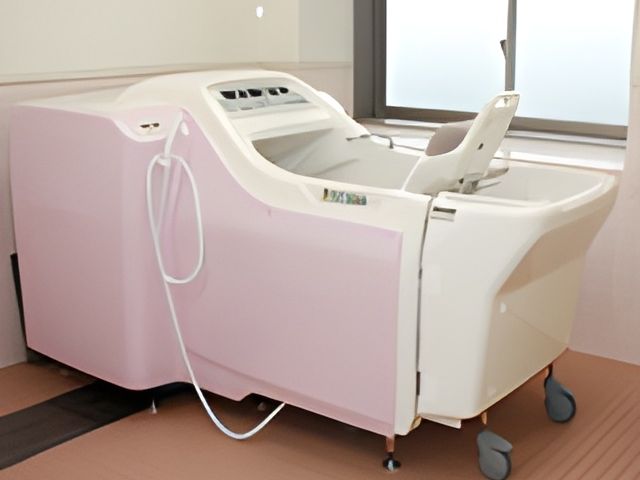 淡いピンク色の浴槽 浴室 柔らかなピンクの浴槽で、利用者が快適に入浴できる設計です。大きな窓から自然光が注ぎます。
