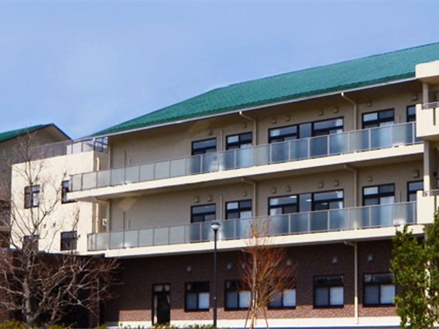 青空の下の建物外観 外観 広々とした施設の建物外観です。明るい空の下で、緑豊かな環境に囲まれています。