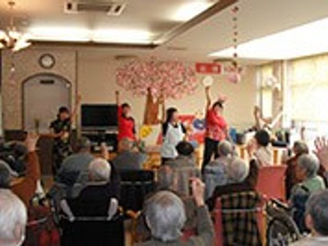 手を上げた人々の部屋 多目的室 広々とした明るい部屋で、多くの方が参加する活気ある催しが行われています。
