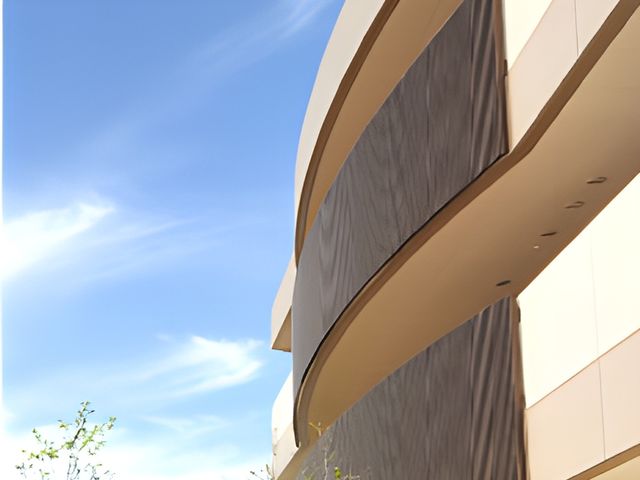 曲線的な外壁のある建物 外観 青い空を背景にした建物は、現代的なデザインが特徴的です。開放感のある設計になっています。