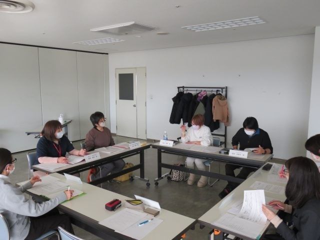 会議室で打ち合わせの様子 多目的室   明るい広さのある会議スペースで、複数の方が机を囲んで話し合っています。就業前の打ち合わせや研修にも使いやすそうです。