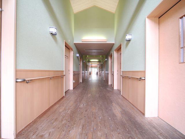 奥行きのある廊下 廊下 自然光が差し込む、落ち着いた雰囲気の通路です。手すりが設置され、安心して移動できます。