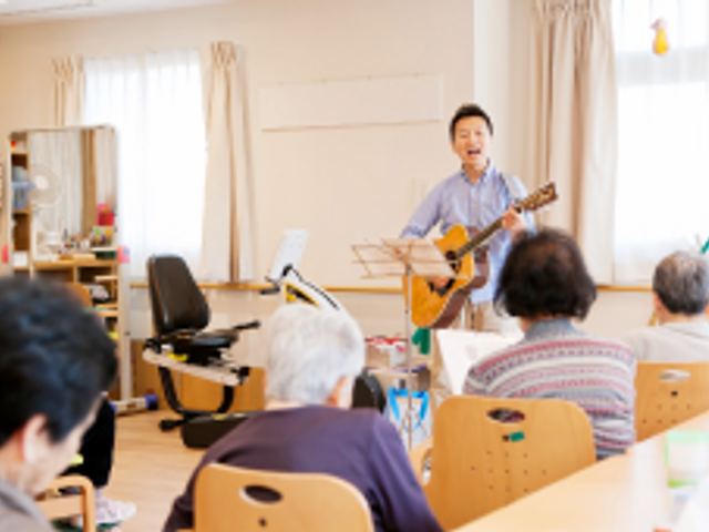 音楽活動の風景 多目的室 自然光が入る部屋で、音楽を楽しむ活動が行われています。和やかな雰囲気です。