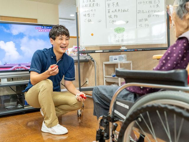 笑顔でレクリエーションをするスタッフ 機能訓練室 明るく元気な対応ができる方を求めています。やりがいのある職場で一緒に笑顔を分かち合いませんか。