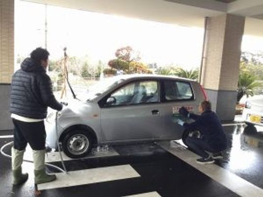 車を拭く人がいる玄関前の外観  