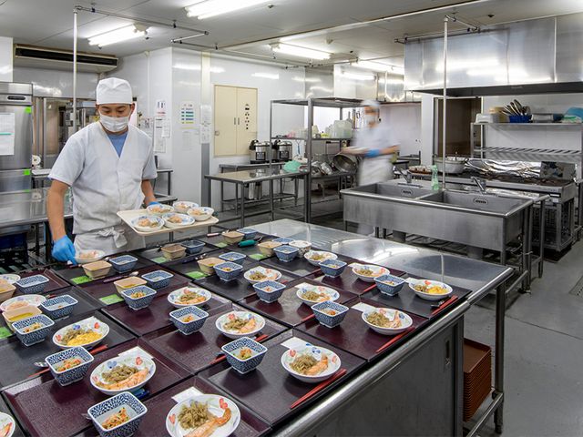 料理を準備中の厨房 キッチン スタッフが料理を準備しています。整然と並べられた料理が目を引く清潔な調理スペースです。