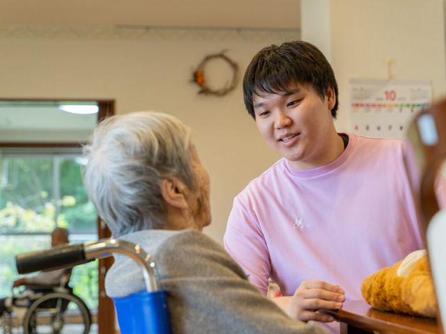 笑顔で接する介護スタッフ リビング 明るいリビングで、利用者様に寄り添うやりがいのある介護のお仕事です。