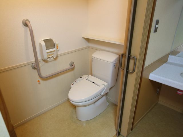 バリアフリートイレ トイレ 安心してご利用いただける、手すり付きの清潔なトイレ空間です。明るい照明が、安全で快適な利用をサポートしています。