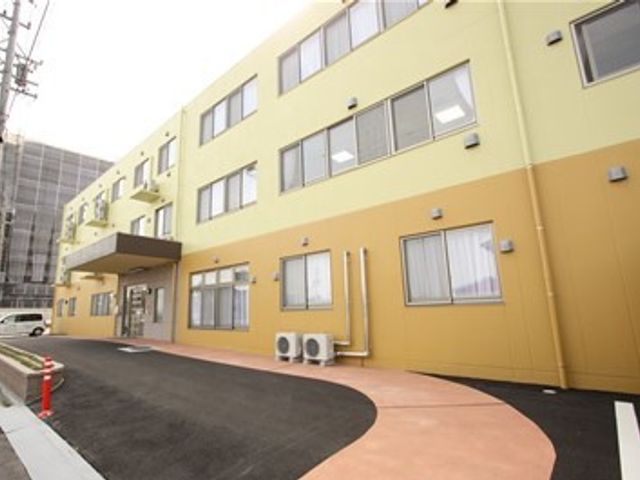 黄色い壁の明るい外観 外観 清潔感があり、親しみやすい色合いの建物です。職員や来訪者が気持ちよく過ごせるよう、心地よい環境が整えられています。