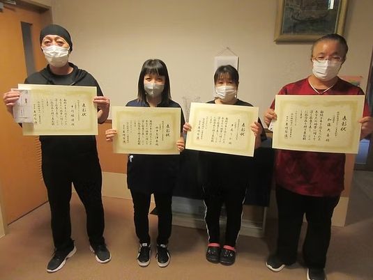 表彰状を持つ4人が並ぶロビー  