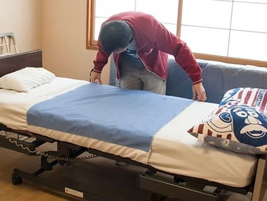 ベッドを整える居室  