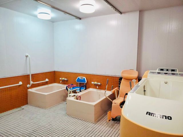設備充実の浴室 浴室 広々とした浴槽が備わった空間で、利用者が快適に入浴を楽しめます。白とオレンジの色調で清潔感があります。