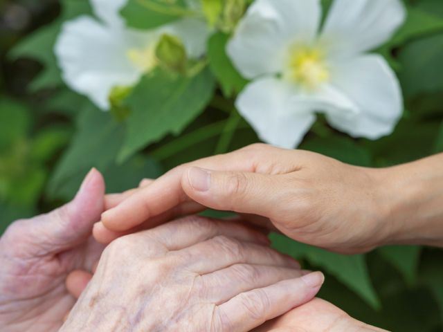 手を握る利用者と介護士 スタッフイメージ 温かい支援が感じられるひとときです。緑に囲まれた落ち着いた環境で安心して働けます。