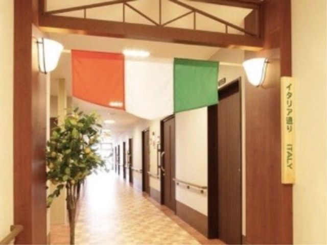 明るい廊下と多色の幕 廊下 温もりのある木目調の廊下には、彩り豊かな幕が飾られ、明るく穏やかな雰囲気を醸し出しています。