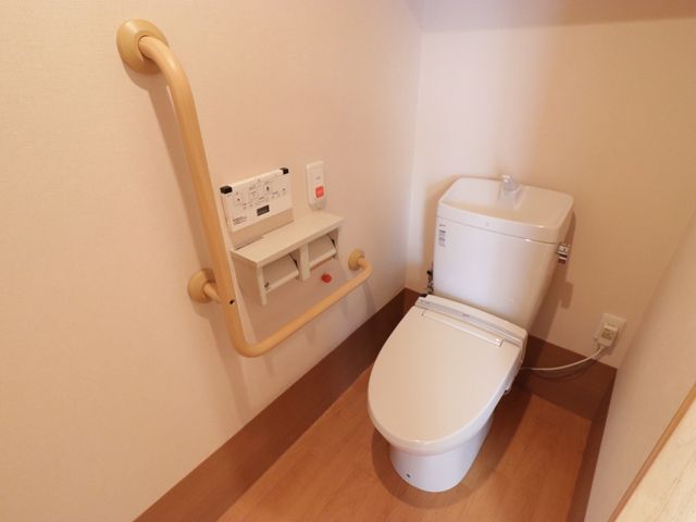 手すり付き清潔なトイレ トイレ 手すりが備わった安全考慮の洋式トイレです。利用者の自立支援と快適性を重視した設計になっています。