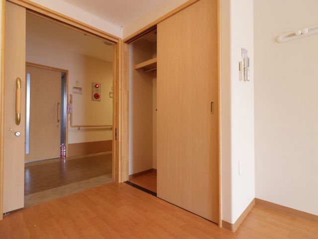 明るい廊下の一角 居室 木目調の壁と床が心地よい温もりを感じさせる廊下です。手すりや広々としたスペースが、安全かつ快適な移動を支えます。