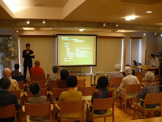 研修会を行う多目的室 運営懇談会 スタッフの方がプレゼンテーションを行う様子。座席には多くの聴講者が注目しています。
