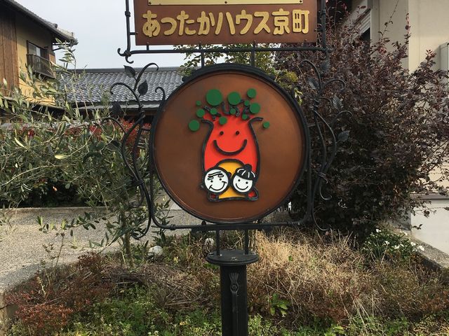 看板と緑の様子 中庭 温かみのあるキャラクターが描かれた案内看板が、訪れる人々を優しく迎え入れています。