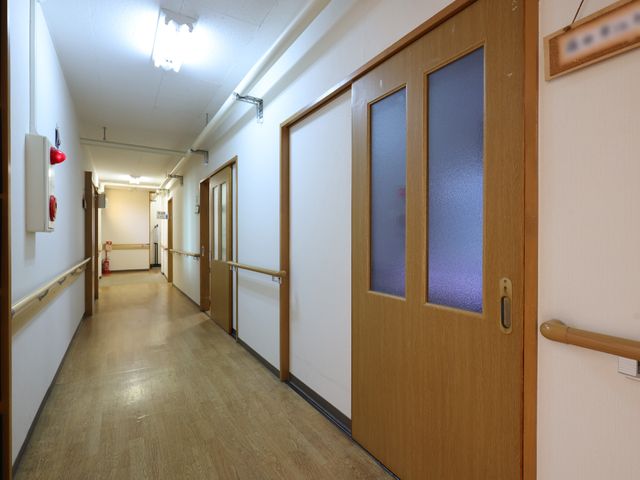 廊下にあるドアと手すり 廊下 手すりが整えられた廊下は、明るく広々としており、日常の移動がしやすい環境です。安全に配慮された設計になっています。