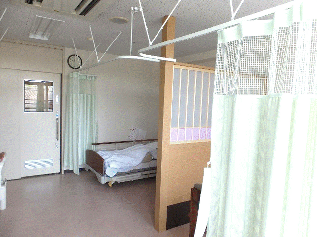 窓から光が差し込む居室 居室 ベッド周りにカーテンが設置され、プライバシーを確保しています。広々とした空間です。