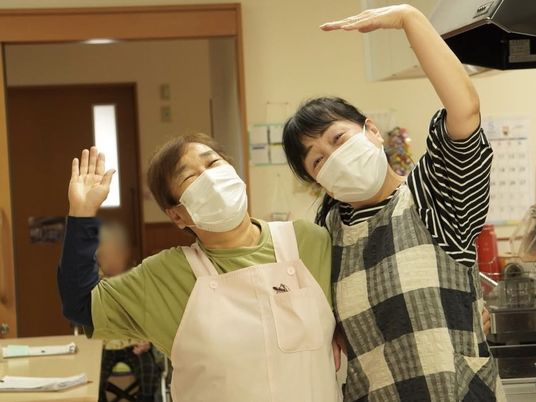 笑顔で手を振る職員と利用者の食堂  