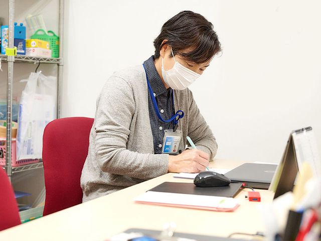 メモを取るスタッフ スタッフイメージ 落ち着いた雰囲気の中で、スタッフが業務に集中している様子です。効率的な業務環境です。