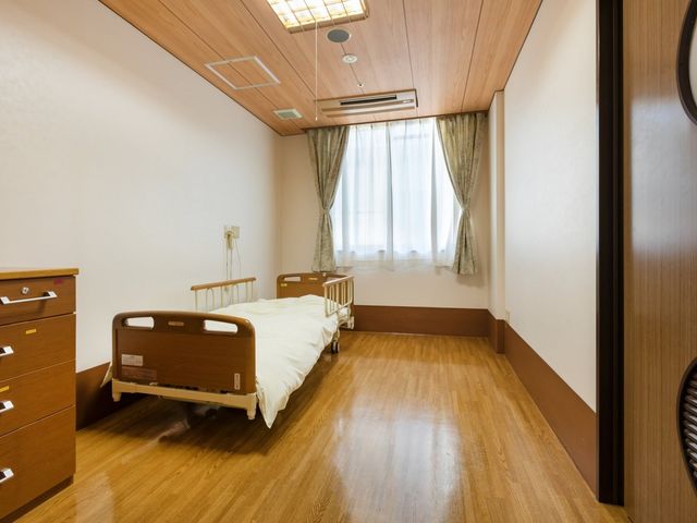 ベッドのある居室 居室 木目調の床と明るいカーテンが特徴の、落ち着いた雰囲気の居室です。自然光がしっかり差し込んでいます。