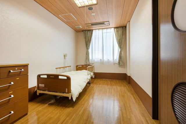 ベッドのある居室 居室 木目調の床と明るいカーテンが特徴の、落ち着いた雰囲気の居室です。自然光がしっかり差し込んでいます。