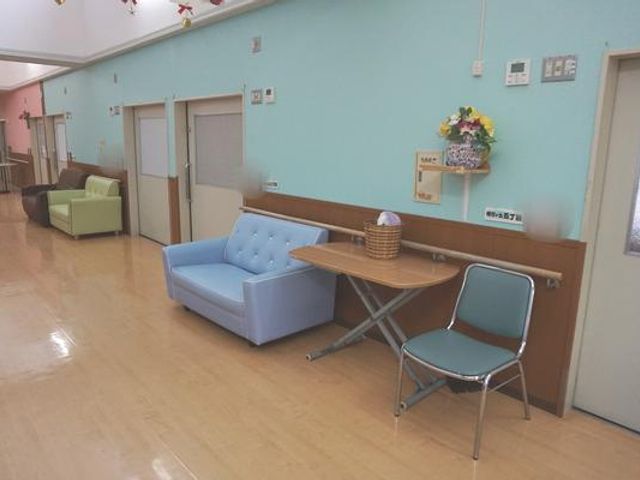 幅広い廊下 廊下 明るい色調の廊下は、利用者が快適に過ごせるスペースを提供しています。リラックスできるソファも配置されています。