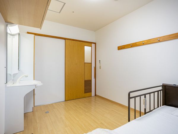 明るい居室の洗面台とベッド  