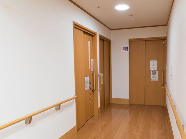 廊下とトイレの案内板 通路 手すりが付いた清潔な廊下は安心して歩ける設計です。トイレも近くにあり、利便性が高まっています。