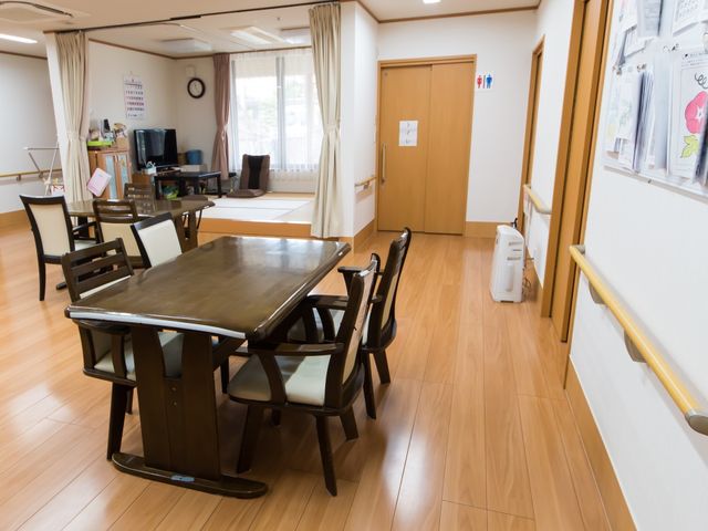 共有スペースの居室 食堂 ゆったりとしたダイニングテーブルが配置され、明るい窓辺でのひとときを過ごせる空間です。掲示物があり、コミュニケーションの場としても機能しています。
