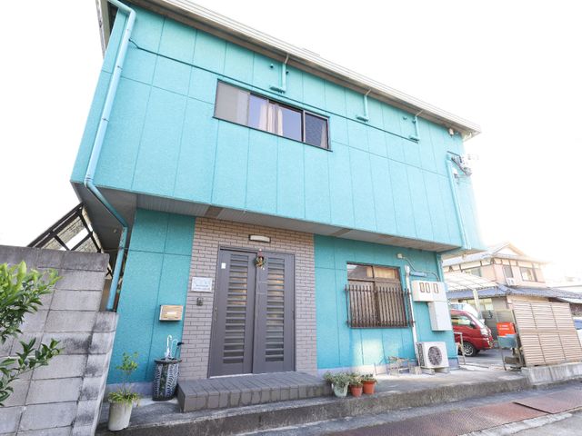 青い外壁の居宅 玄関 ゆったりとした門構えのある落ち着いた色合いの建物です。周辺は静かで、働きやすい環境が整っています。