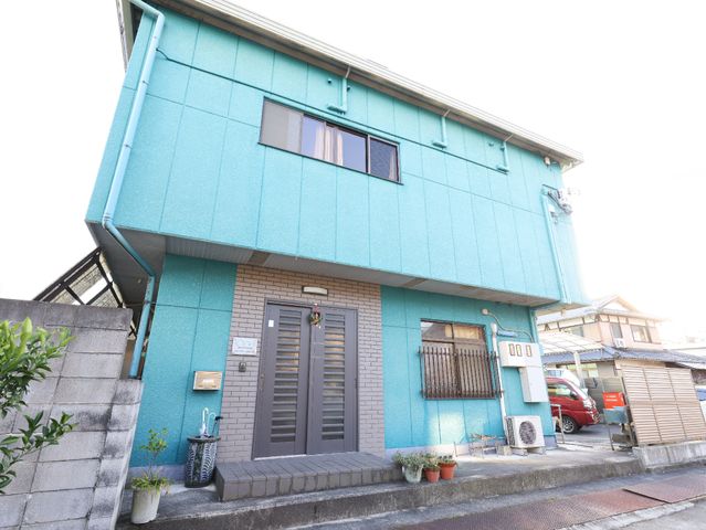 青い外壁の居宅 玄関 ゆったりとした門構えのある落ち着いた色合いの建物です。周辺は静かで、働きやすい環境が整っています。