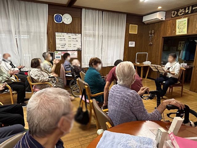 談話が行われる共有スペース ラウンジ 自然光が差し込む暖かい雰囲気の部屋で、皆さんが椅子に座りお話を楽しんでいます。
