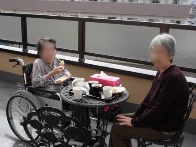 テラスでお茶する人たち 入居者様 ゆったりとお茶を楽しむ憩息の時間です。車椅子の方も参加でき、温かいコミュニケーションが生まれる空間が広がっています。