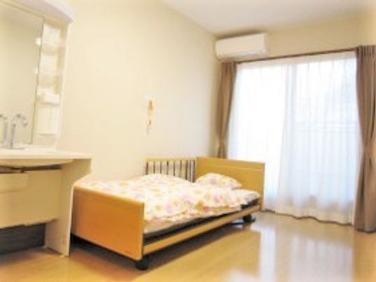 フローリングのシンプルな居室にはカーテンや洗面、ベッドが付いている。
