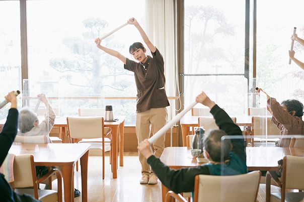 笑顔で運動指導するスタッフと利用者たちの様子