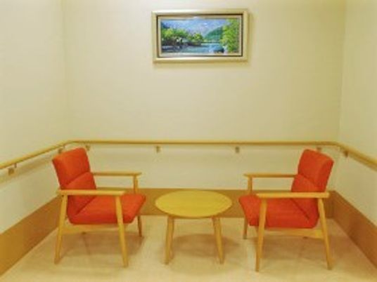 手すりが設置された共有スペースには赤い椅子が2脚と丸いテーブルが置かれている。